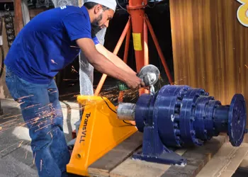 Machinist precision-cutting a steel sprocket on a lathe